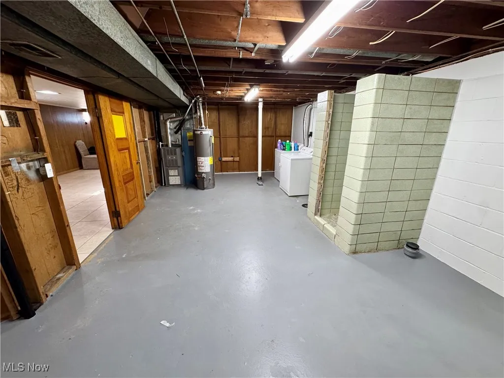 Unfinished basement with water heater, heating unit, and separate washer and dryer