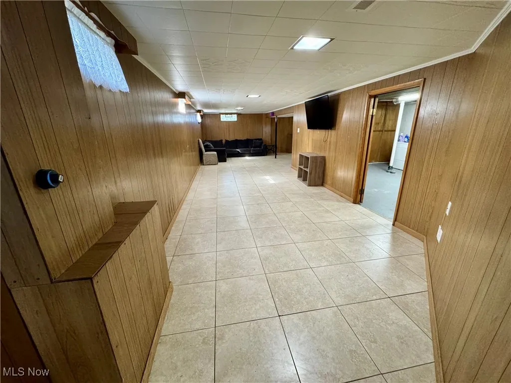 Corridor with light tile patterned floors and wooden walls