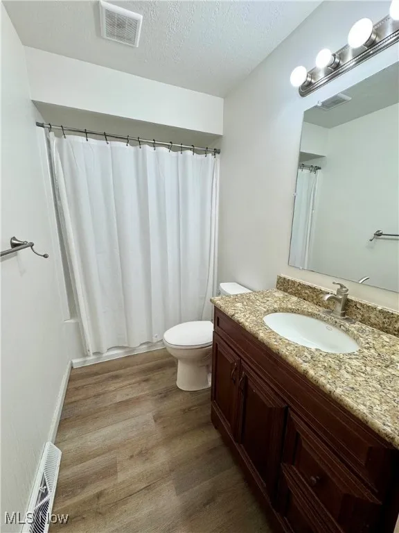 Bathroom featuring vanity, a textured ceiling, dark wood-style floors, and a shower with curtain