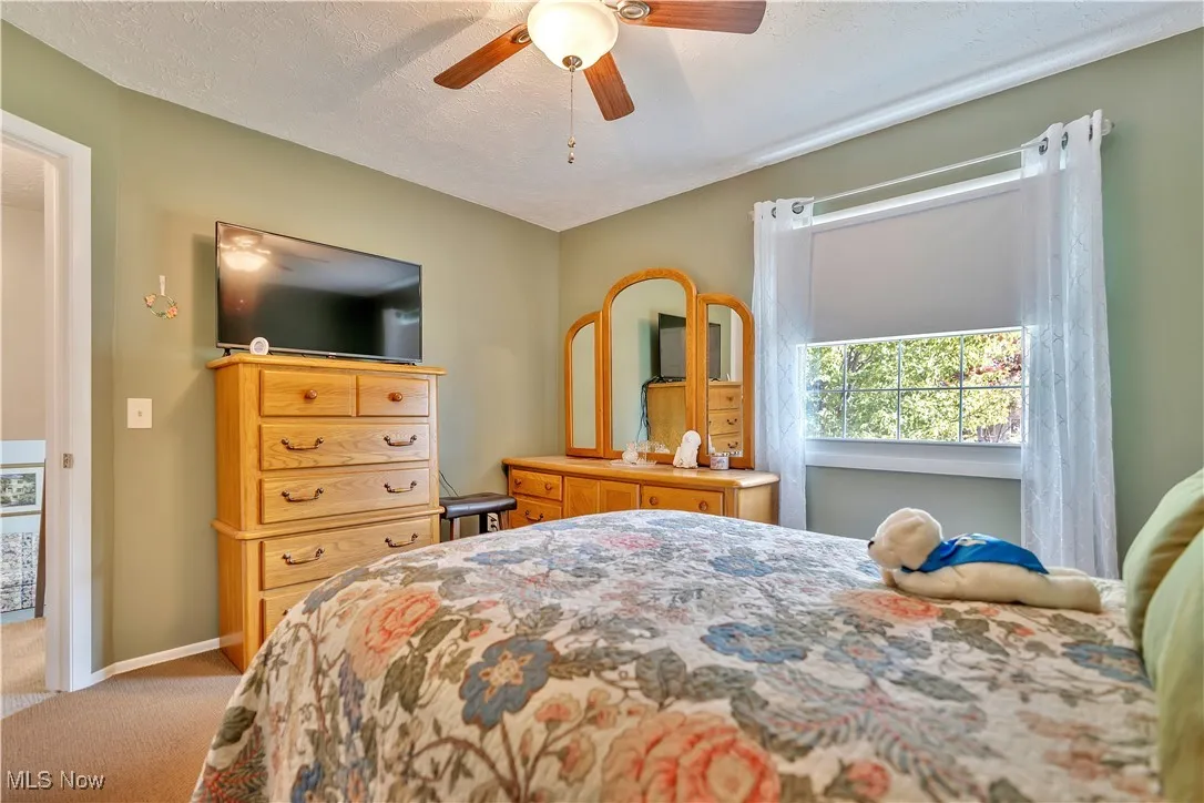Bedroom with a textured ceiling, light colored carpet, and ceiling fan