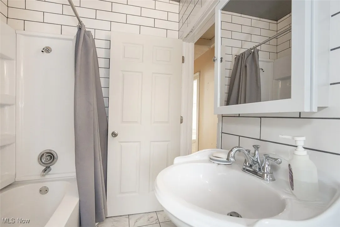 Bathroom with a sink and shower / bathtub combination with curtain