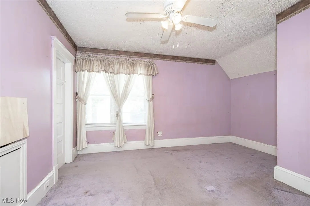Bonus room featuring a textured ceiling, carpet floors, vaulted ceiling, and a ceiling fan