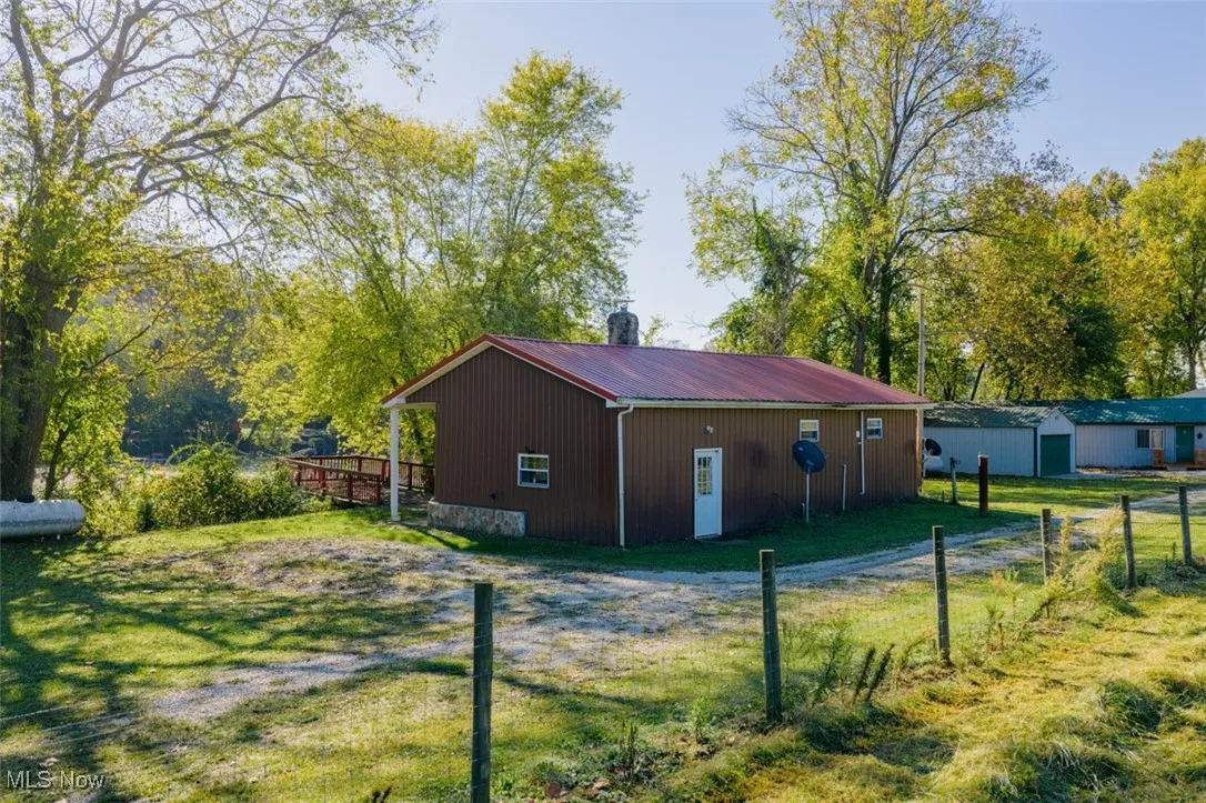 View of side of property featuring a metal roof, an outdoor structure, a pole building, and a lawn
