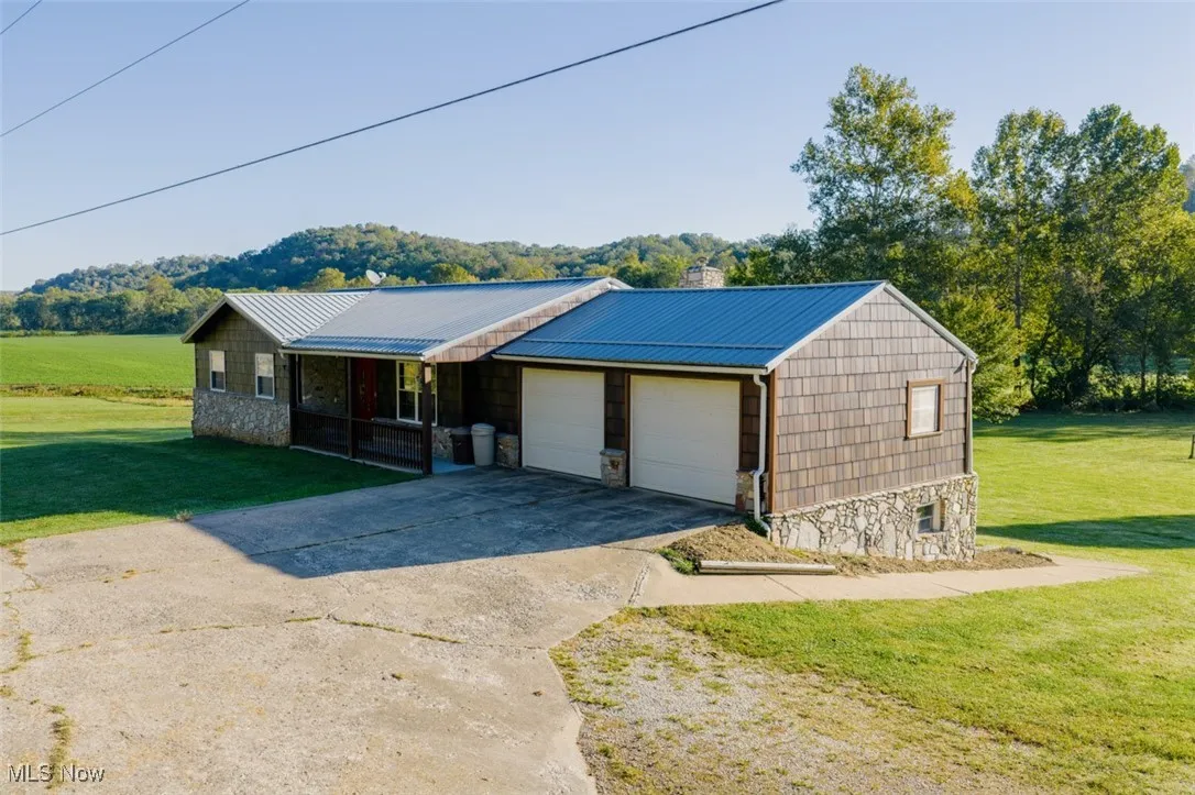 Single story home with stone siding, a front yard, a chimney, and a metal roof