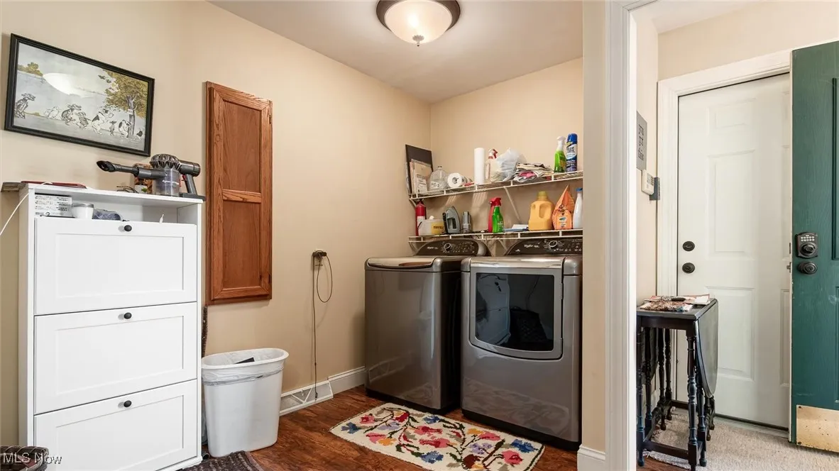 Laundry room with dark wood-style floors and independent washer and dryer
