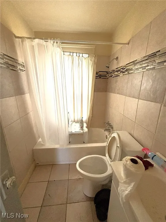 Full bath featuring tile walls, shower / tub combo, tile patterned floors, and a textured ceiling