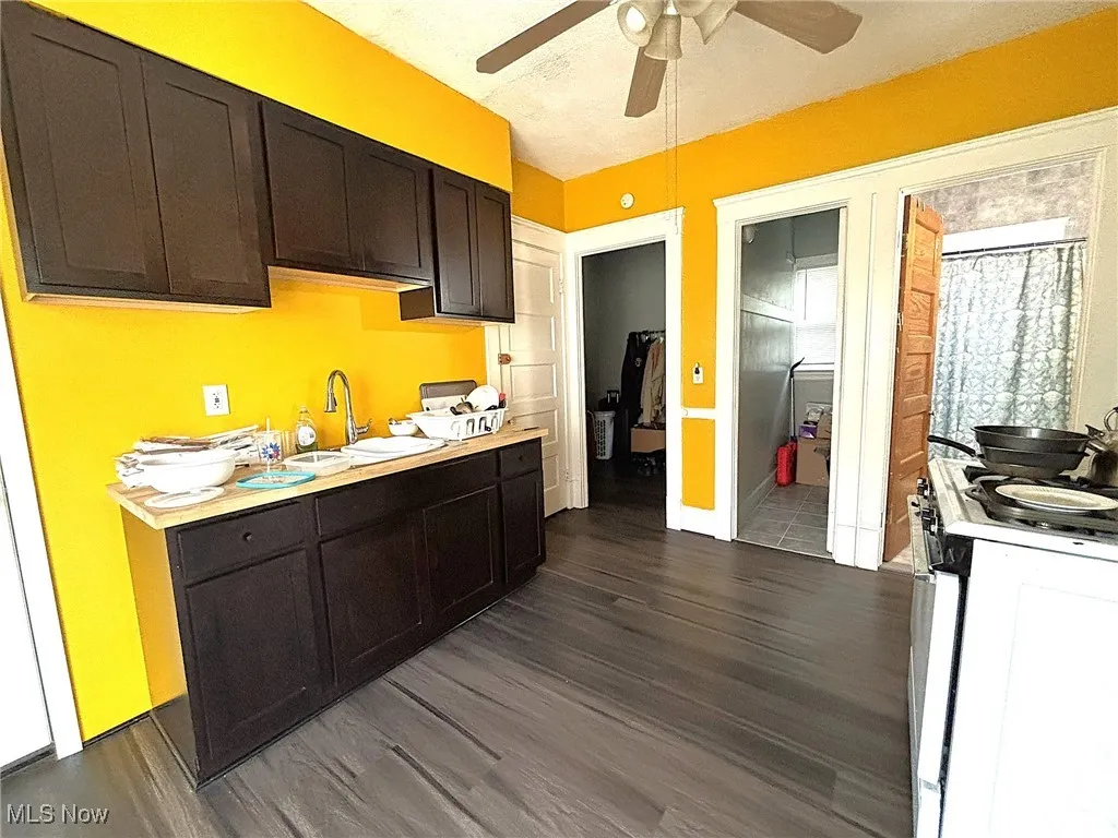 Kitchen with light countertops, range, dark wood-style floors, and a ceiling fan
