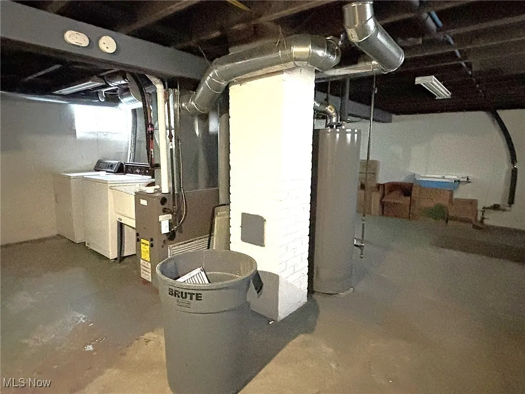 Unfinished below grade area featuring water heater, heating unit, and washer and dryer