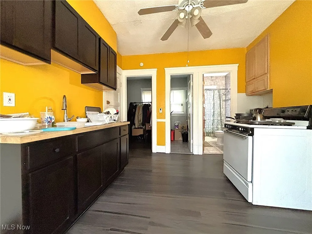 Kitchen featuring white gas range oven, light countertops, dark wood-style floors, and a ceiling fan