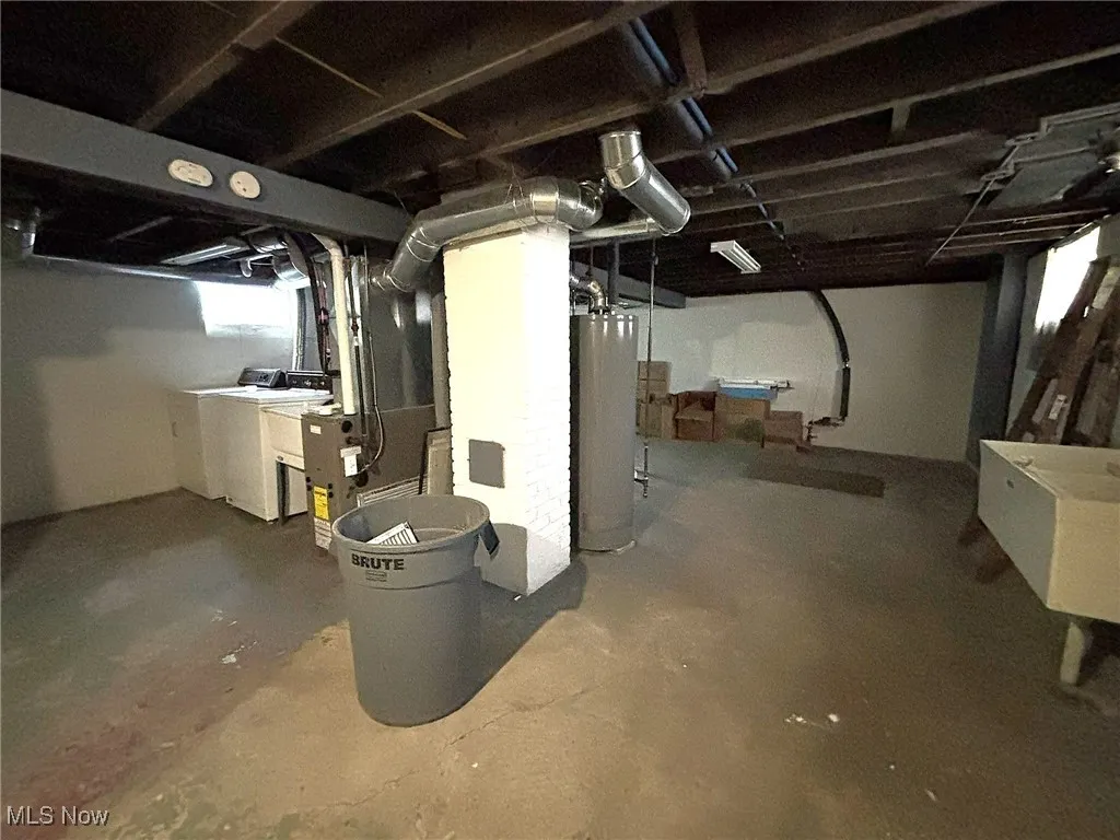 Below grade area featuring water heater, heating unit, and independent washer and dryer
