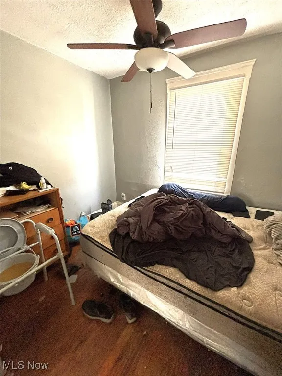 Bedroom featuring a textured ceiling, wood finished floors, and ceiling fan