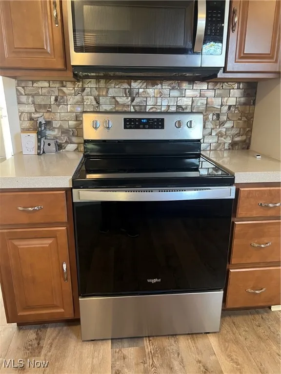Kitchen with appliances with stainless steel finishes, decorative backsplash, and brown cabinetry