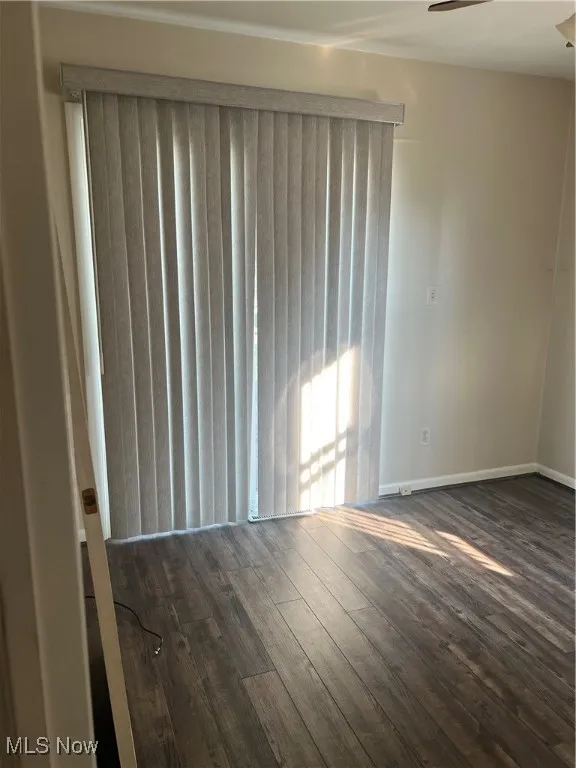 Empty room with dark wood-type flooring and ceiling fan