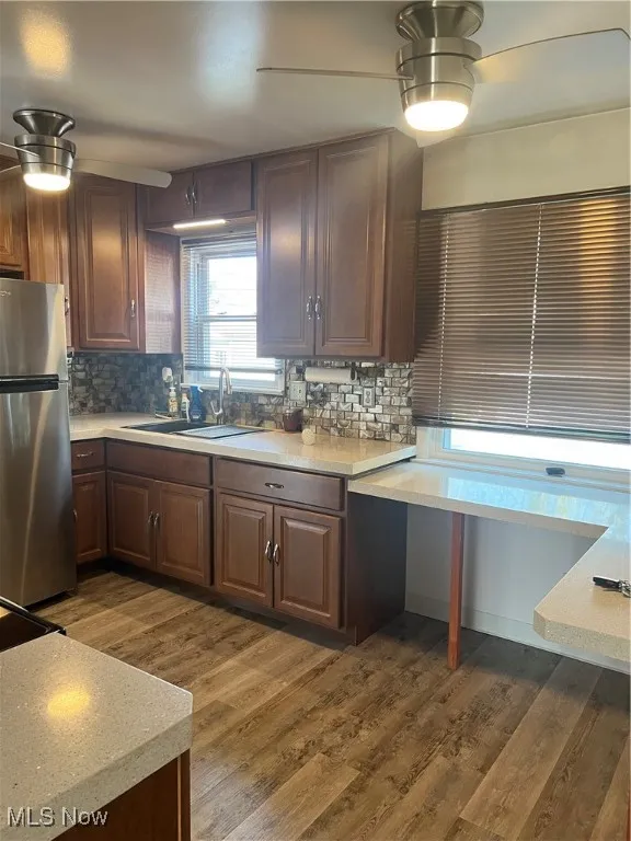 Kitchen with ceiling fan, dark wood-style floors, fridge, and backsplash