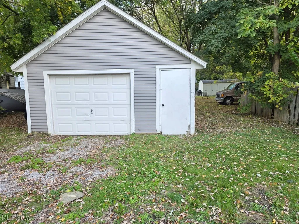Detached garage with heating fuel and view of wooded area