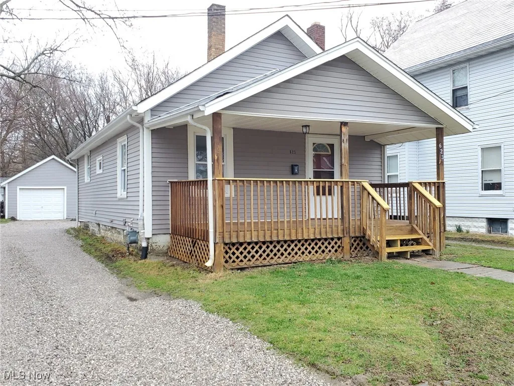 Bungalow with an outdoor structure, a chimney, a front yard, a detached garage, and driveway