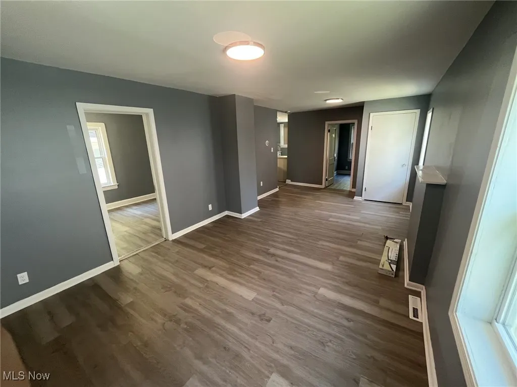 Spare room featuring dark wood-style floors and baseboards