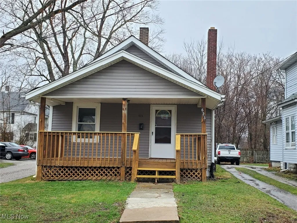 View of front of home with covered porch, a chimney, and a front lawn