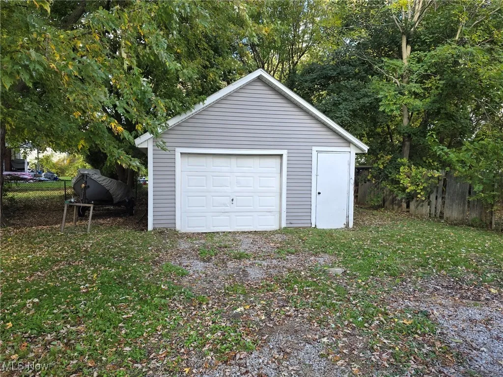 Detached garage with view of wooded area and driveway