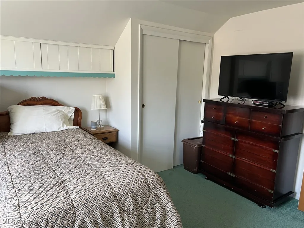 Carpeted bedroom with a closet and vaulted ceiling