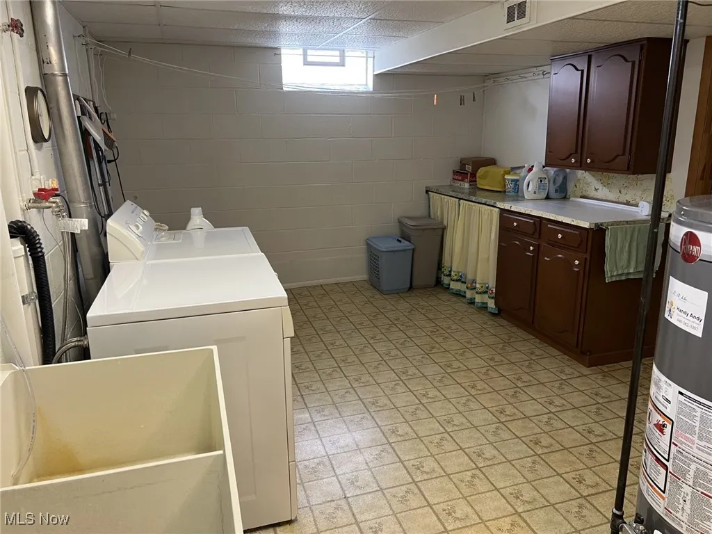 Laundry area with gas water heater, a paneled ceiling, light floors, and washer and dryer