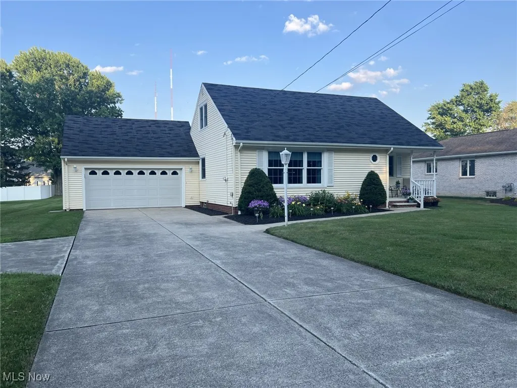 View of front of property featuring a front lawn, driveway, an attached garage, and a shingled roof