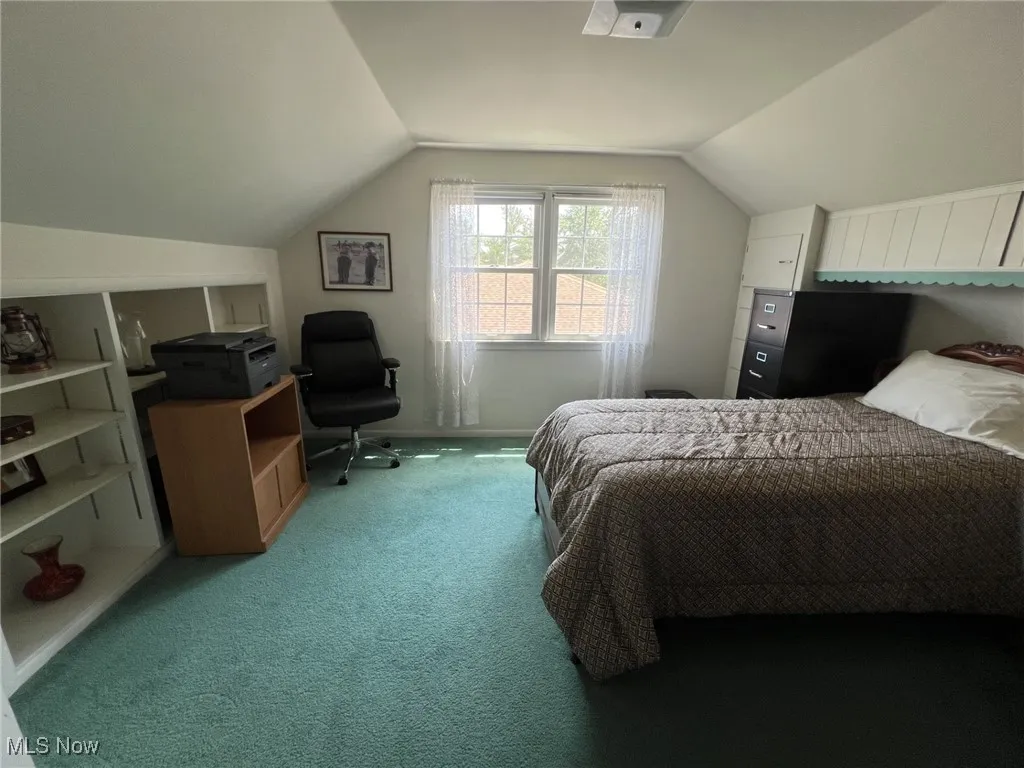 Carpeted bedroom with vaulted ceiling and baseboards