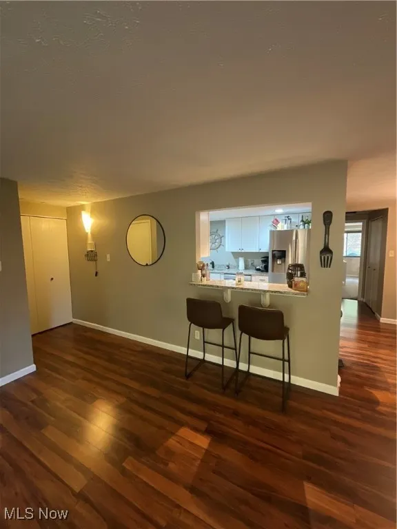 Living room featuring dark wood-style floors and baseboards