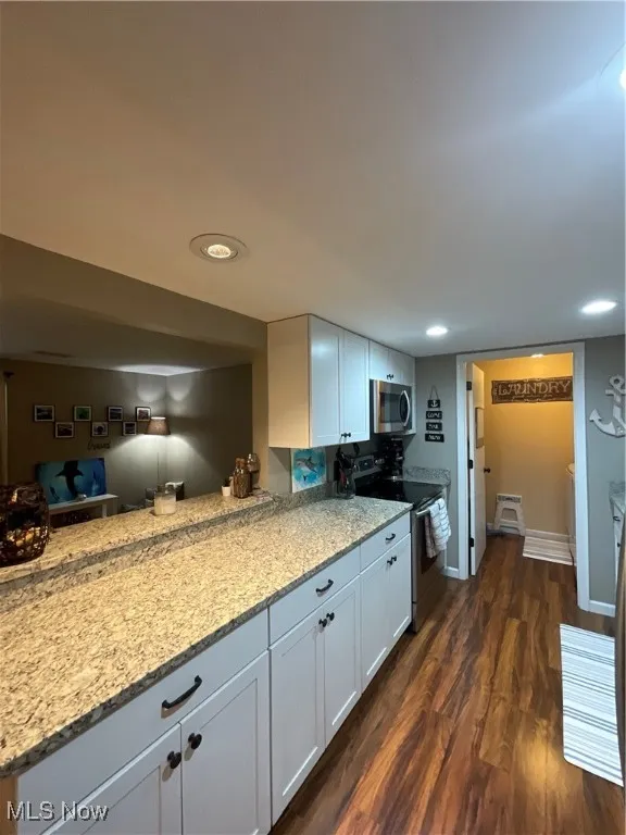 Kitchen with range with electric stovetop, white cabinetry, light stone counters, and dark wood finished floors