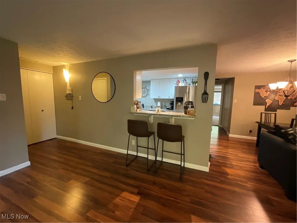 Kitchen with refrigerator, pendant lighting, a kitchen bar, dark wood finished floors, and a peninsula