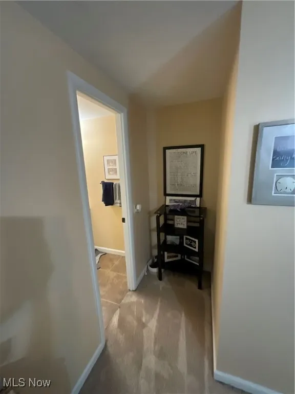 Hall with light colored carpet and baseboards
