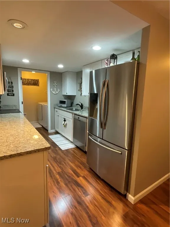 Kitchen featuring stainless steel appliances, dark wood-style flooring, recessed lighting, light stone countertops, and independent washer and dryer