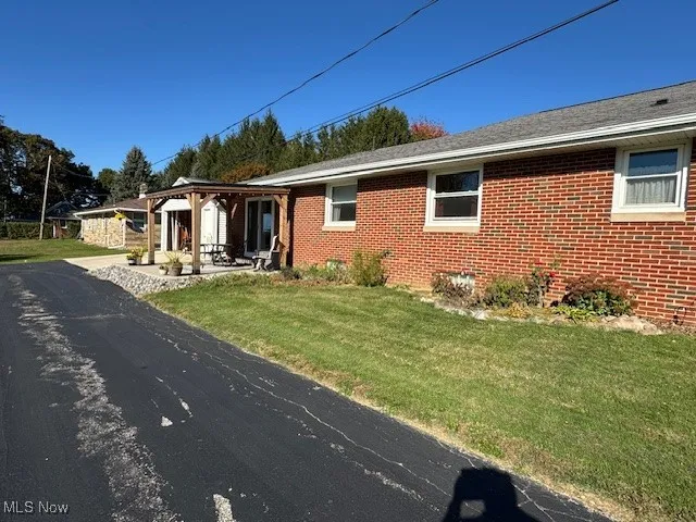 View of side of property featuring brick  and a front lawn