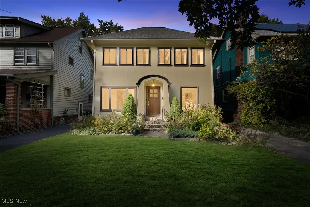 View of front of home featuring stucco siding, a yard, and roof with shingles