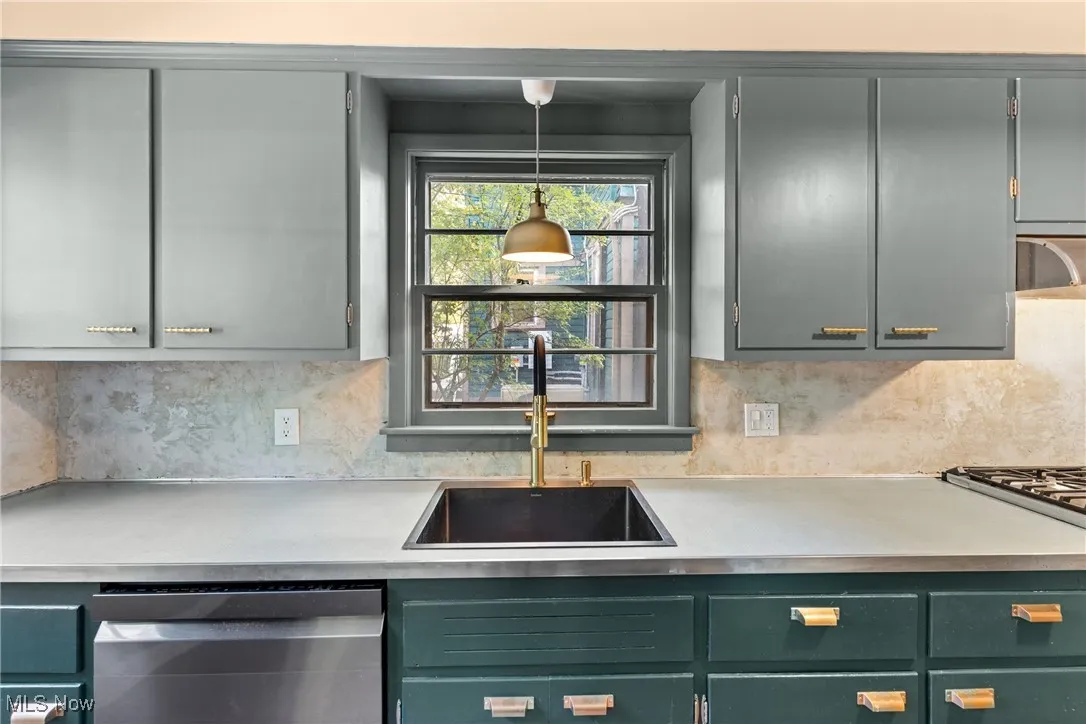 Kitchen featuring appliances with stainless steel finishes, light countertops, decorative backsplash, and decorative light fixtures