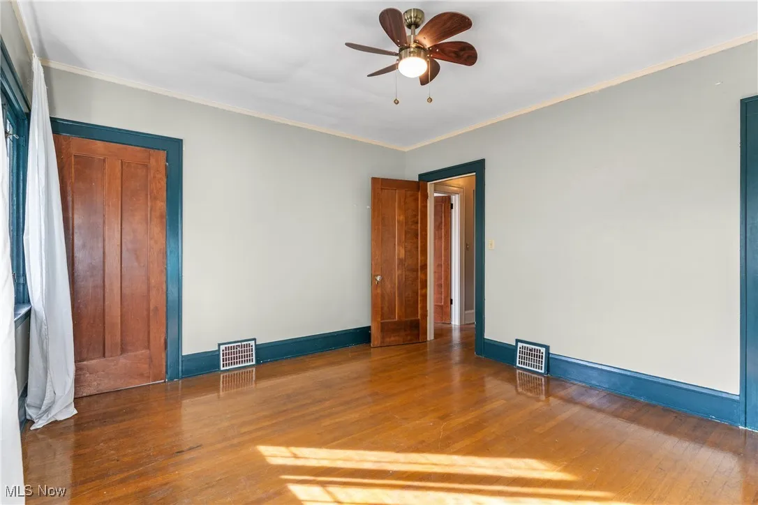 Spare room with hardwood / wood-style flooring, ornamental molding, and a ceiling fan
