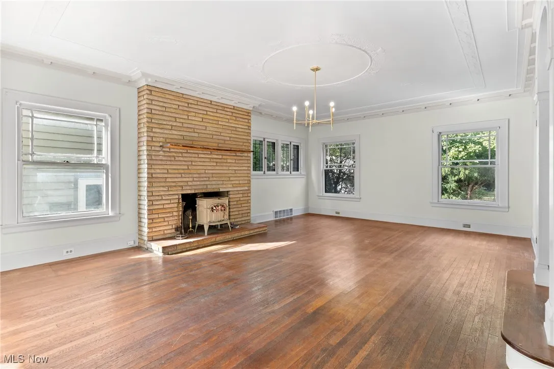 Unfurnished living room featuring wood-type flooring, a fireplace, and a chandelier