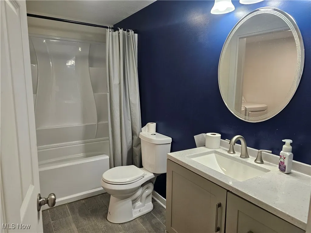 Hall Bathroom with vanity, shower / bath combo with shower curtain.