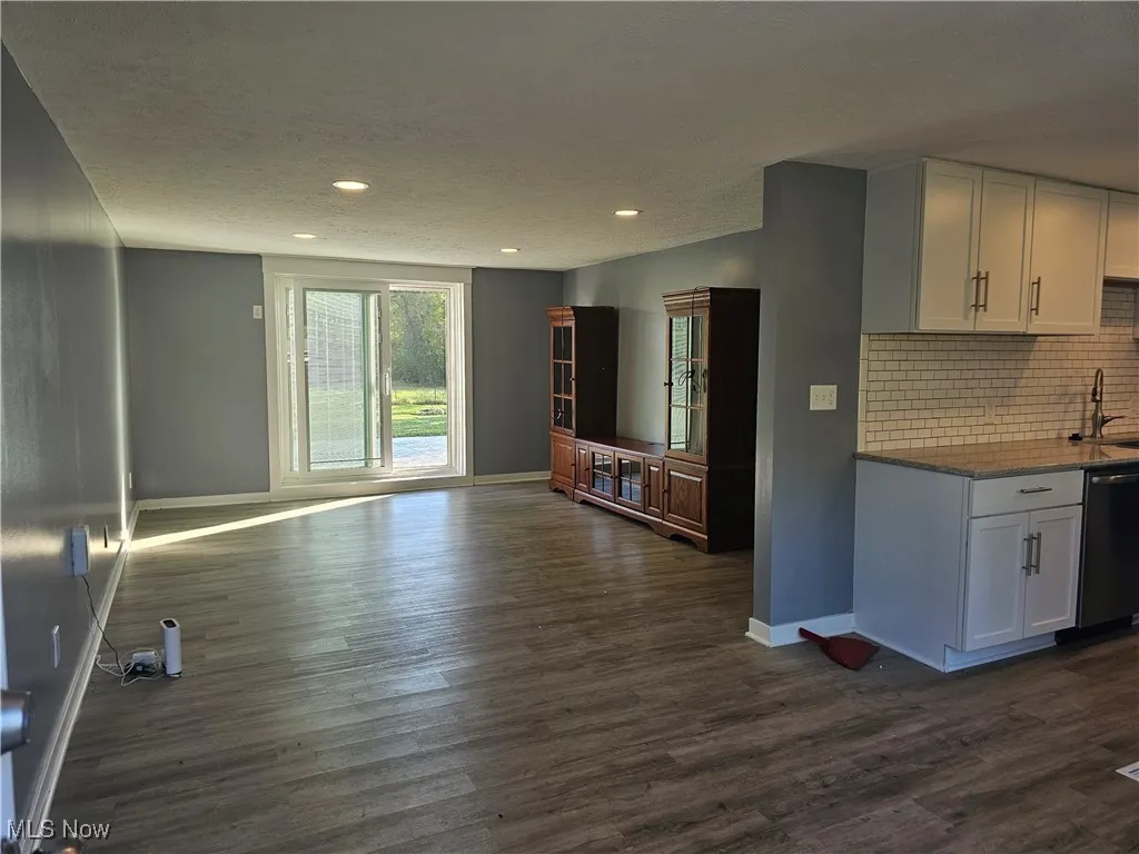 Kitchen featuring backsplash, white cabinetry at at the end of the living room.