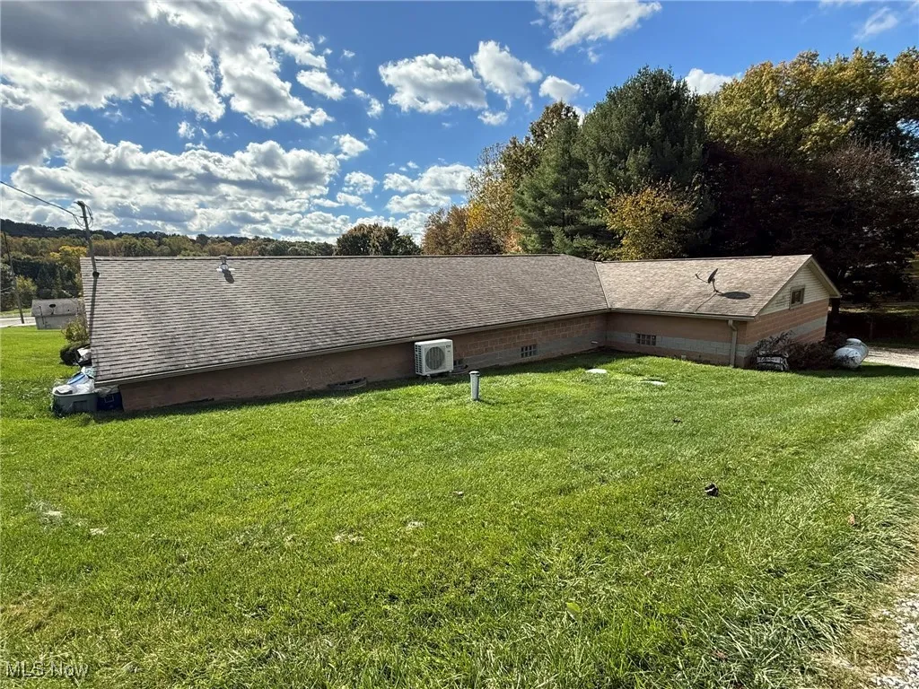 View of side of property featuring a yard and a shingled roof