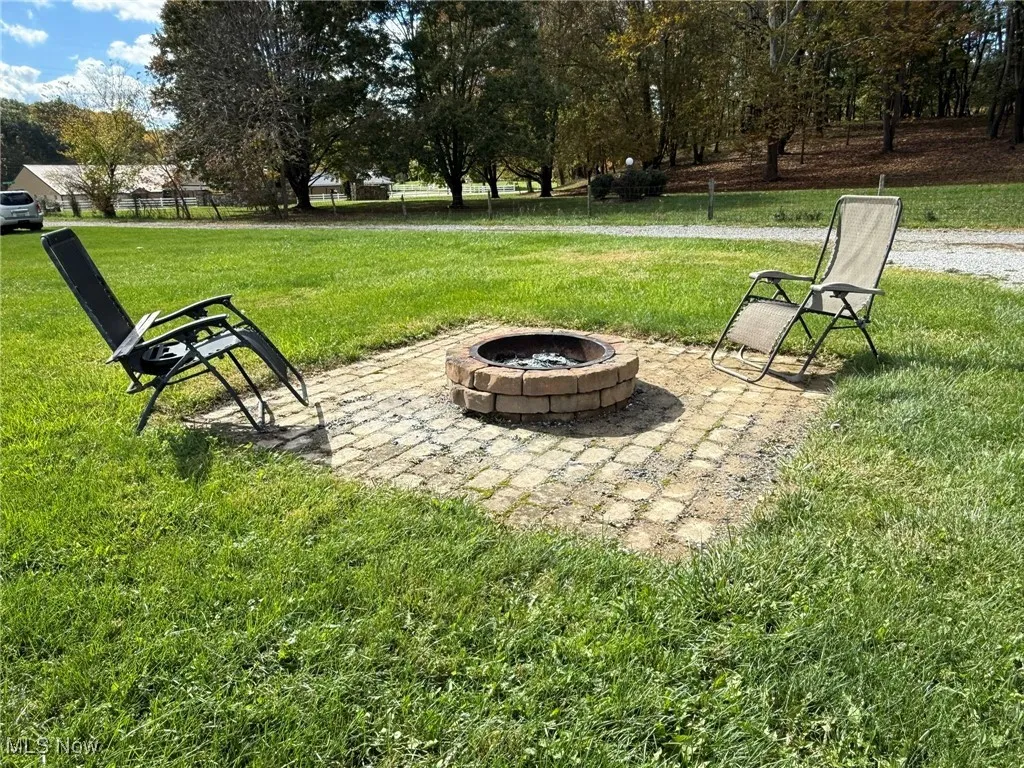 View of grassy yard with a patio and an outdoor fire pit