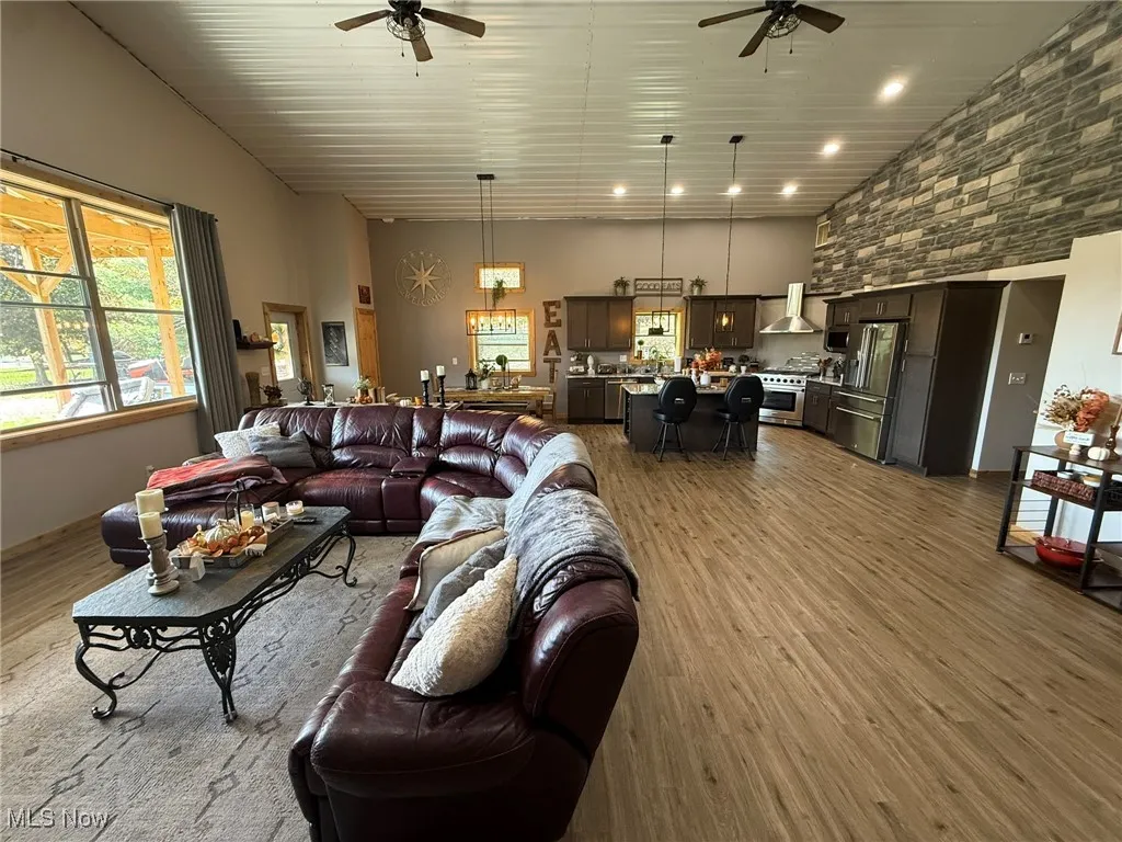 Living area with light wood finished floors, a ceiling fan, and a high ceiling