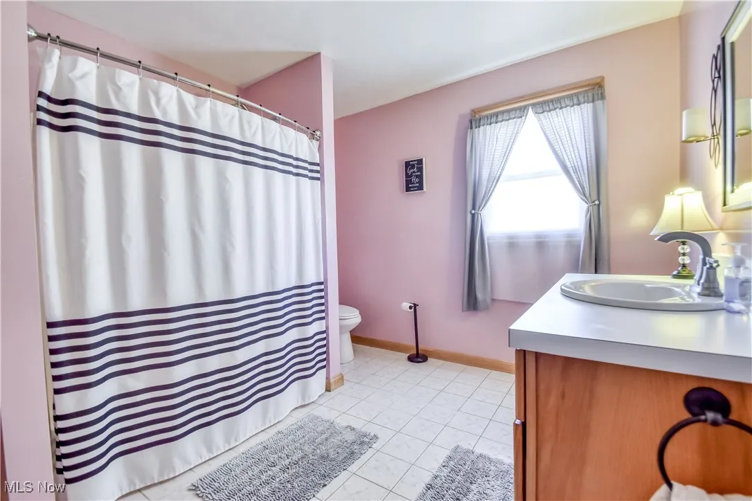 Bathroom with a shower with curtain, vanity, and light tile patterned flooring