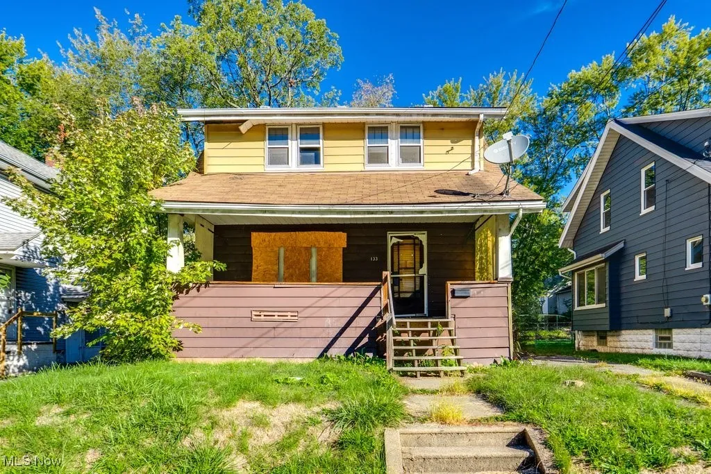 View of front of property featuring stairs, covered porch, and a shingled roof
