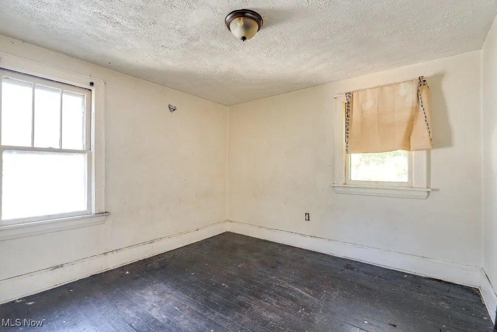Empty room with dark wood-type flooring and a textured ceiling