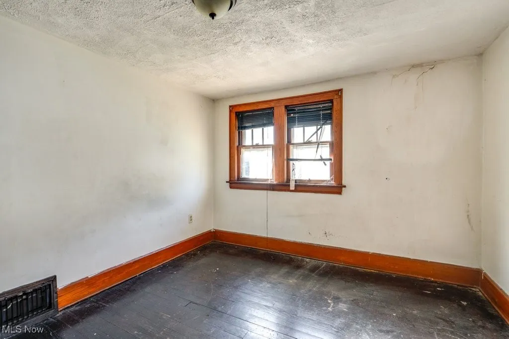 Spare room with dark wood-type flooring and a textured ceiling