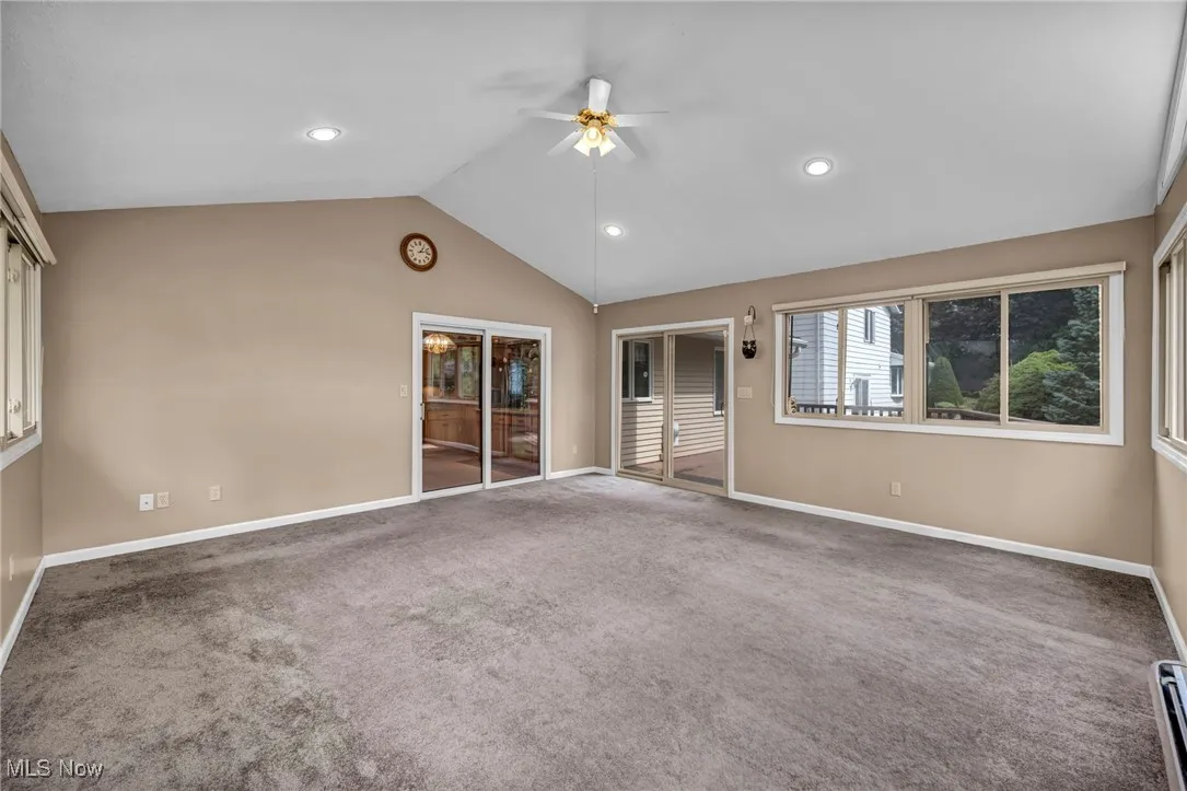 Spare room featuring carpet, lofted ceiling, ceiling fan, a baseboard heating unit, and recessed lighting