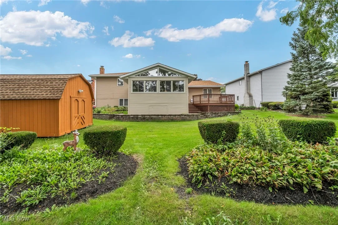 Back of house featuring a storage unit, a lawn, and a deck
