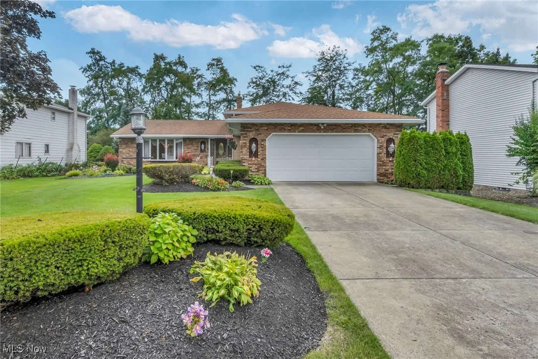 Single story home with a front lawn, a garage, concrete driveway, brick siding, and roof with shingles