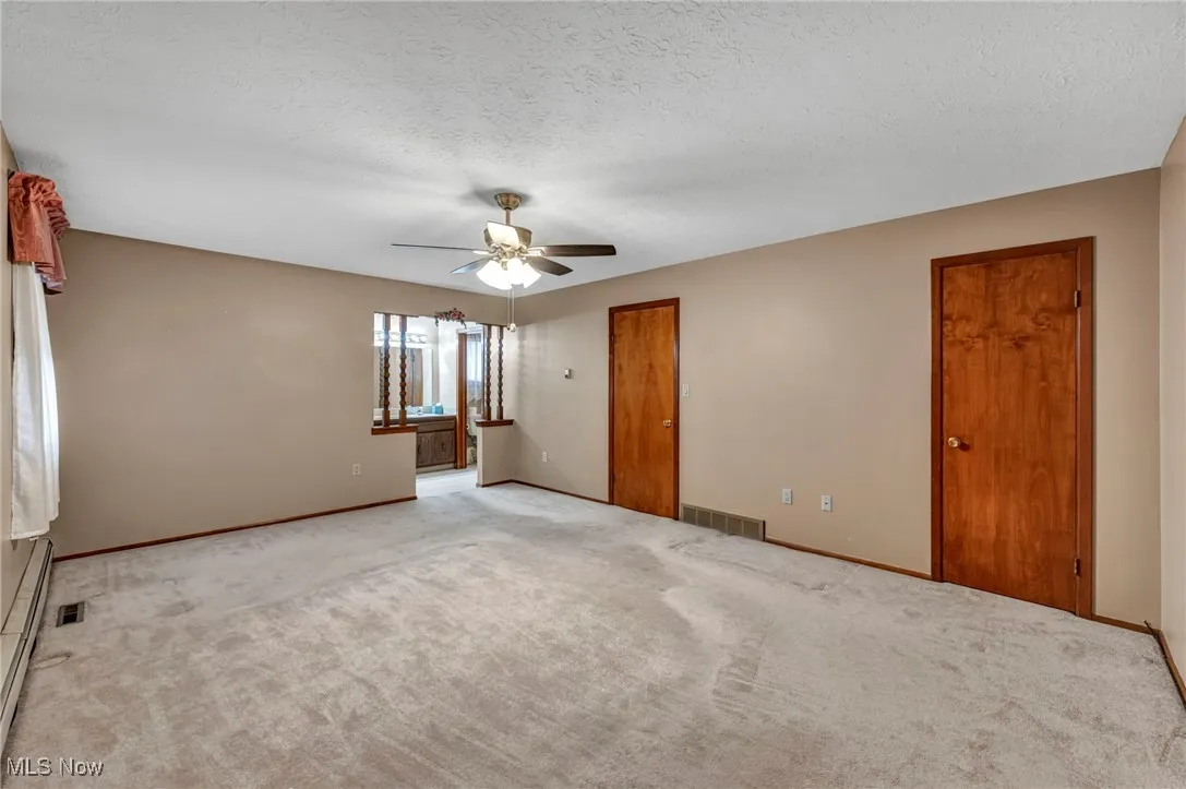 Unfurnished bedroom with carpet flooring, a baseboard heating unit, a textured ceiling, and ceiling fan
